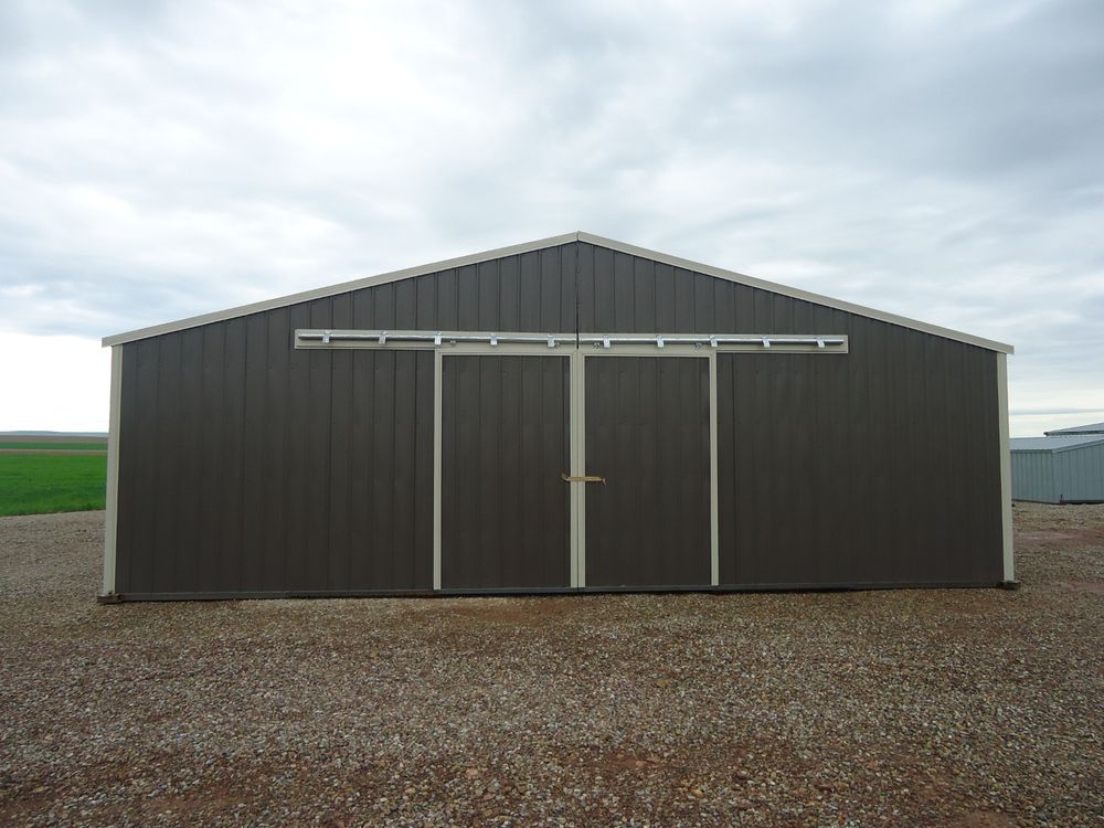 Gable end of the 34 by 48 foot enclosed calving barn in burnished slate with light stone trim and double sliding doors