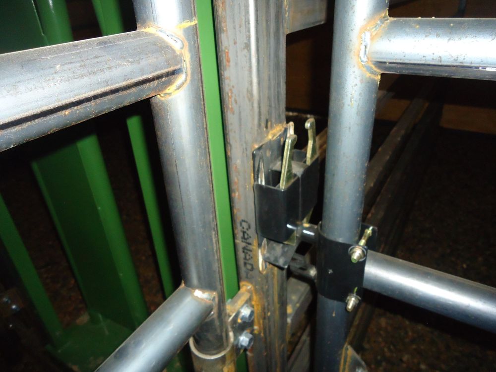 Close up of a heavy duty bull gate latch and hinge on a steel pen panel