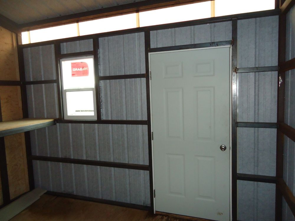 Interior of the insulated tack room with a shelf, a window and a steel man door
