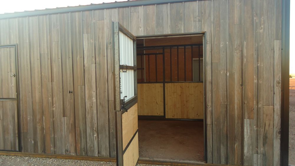 Custom built metal dutch door standing open on the exterior of a woodgrain metal barn, showing the wood lined stall inside