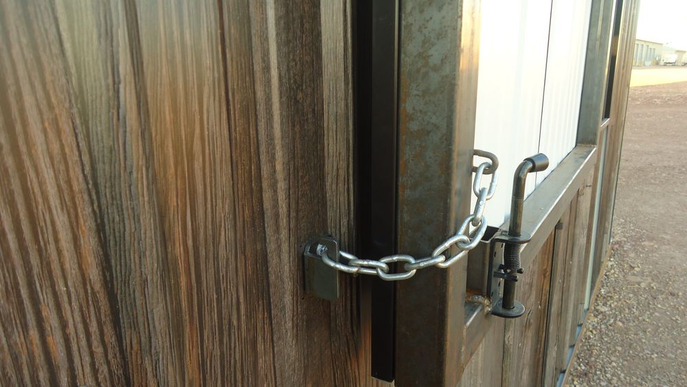 Close up of the chain latch hardware and the antique barnwood plank texture of the 26 gauge woodgrain steel siding